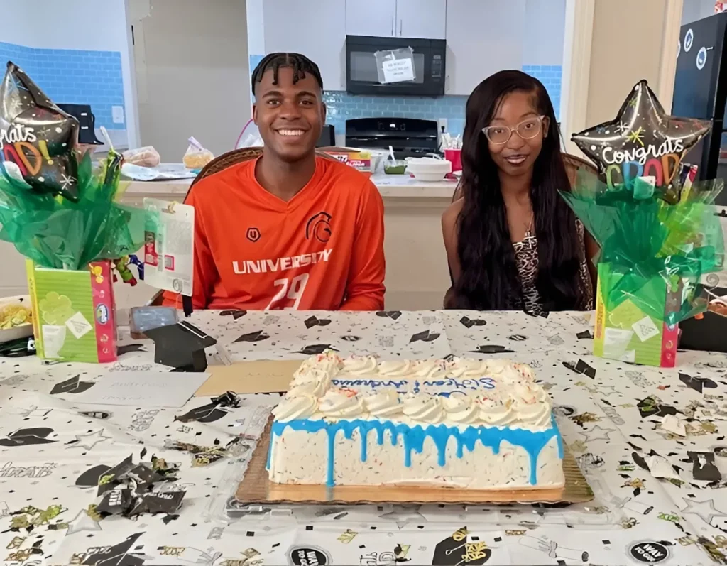 ImpowerFL youth graduates celebrating a milestone achievement with a graduation cake and gifts at a supportive residential program